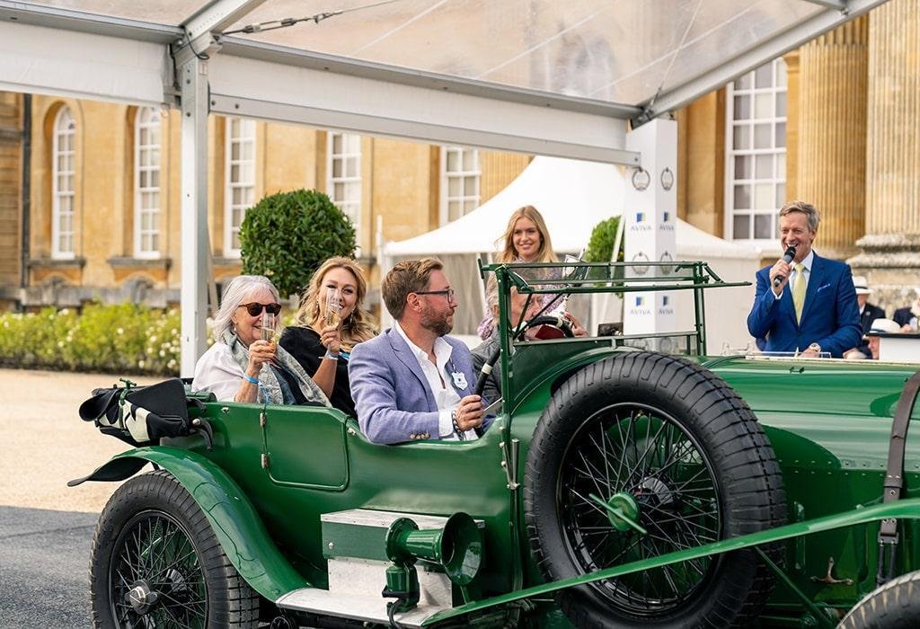 People in a luxury green car enjoying white wine in a glass and smiling