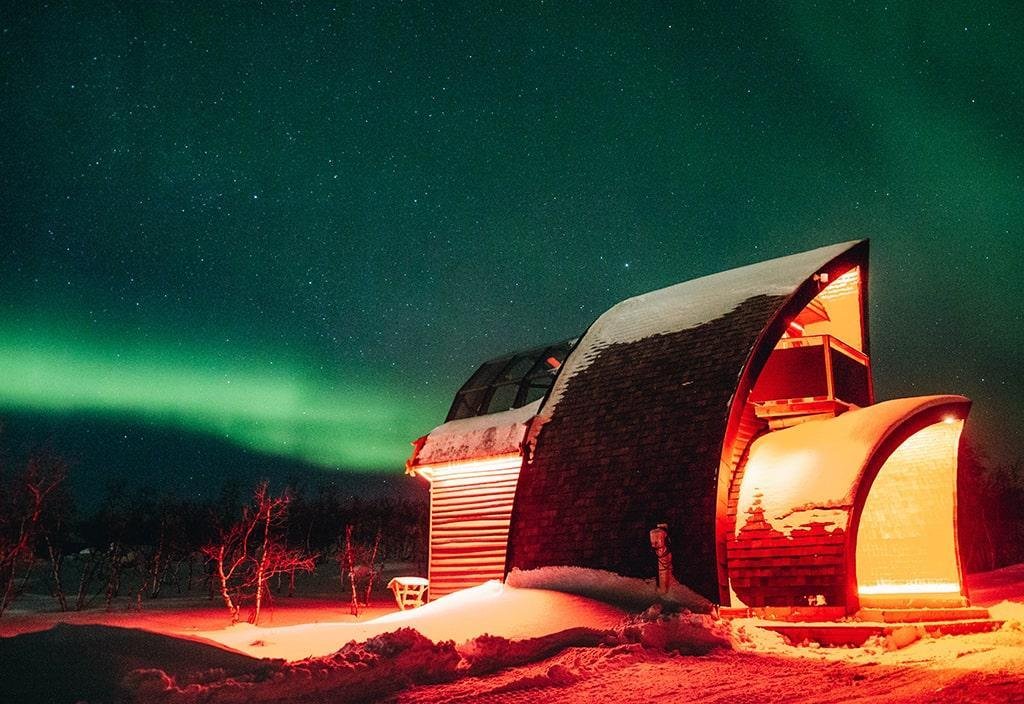 The glass igloo cabin with the Northern lights in the background