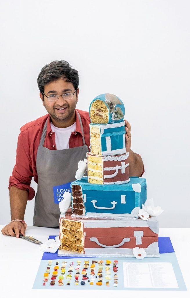 The baker Rahul Mandal standing behind his cake that has been cut through the edge to reveal the inside of each layer 
