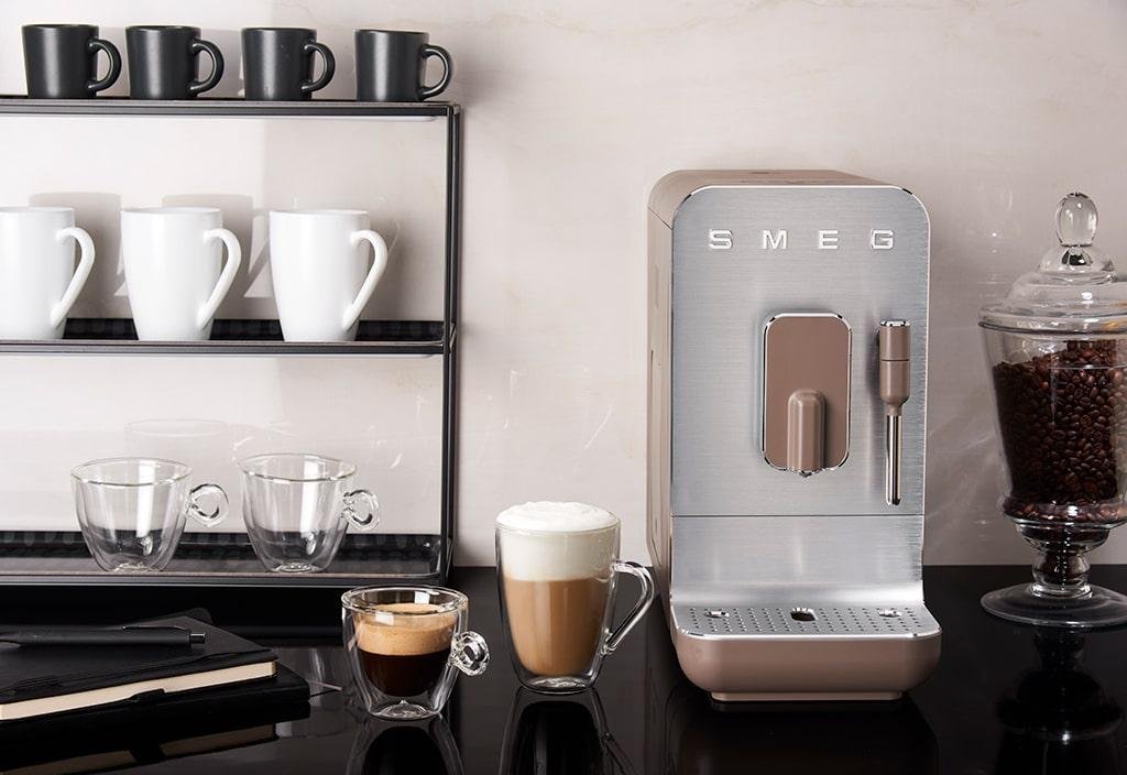 The coffee machine on a black countertop next to a cappuccino, espresso and many empty cups